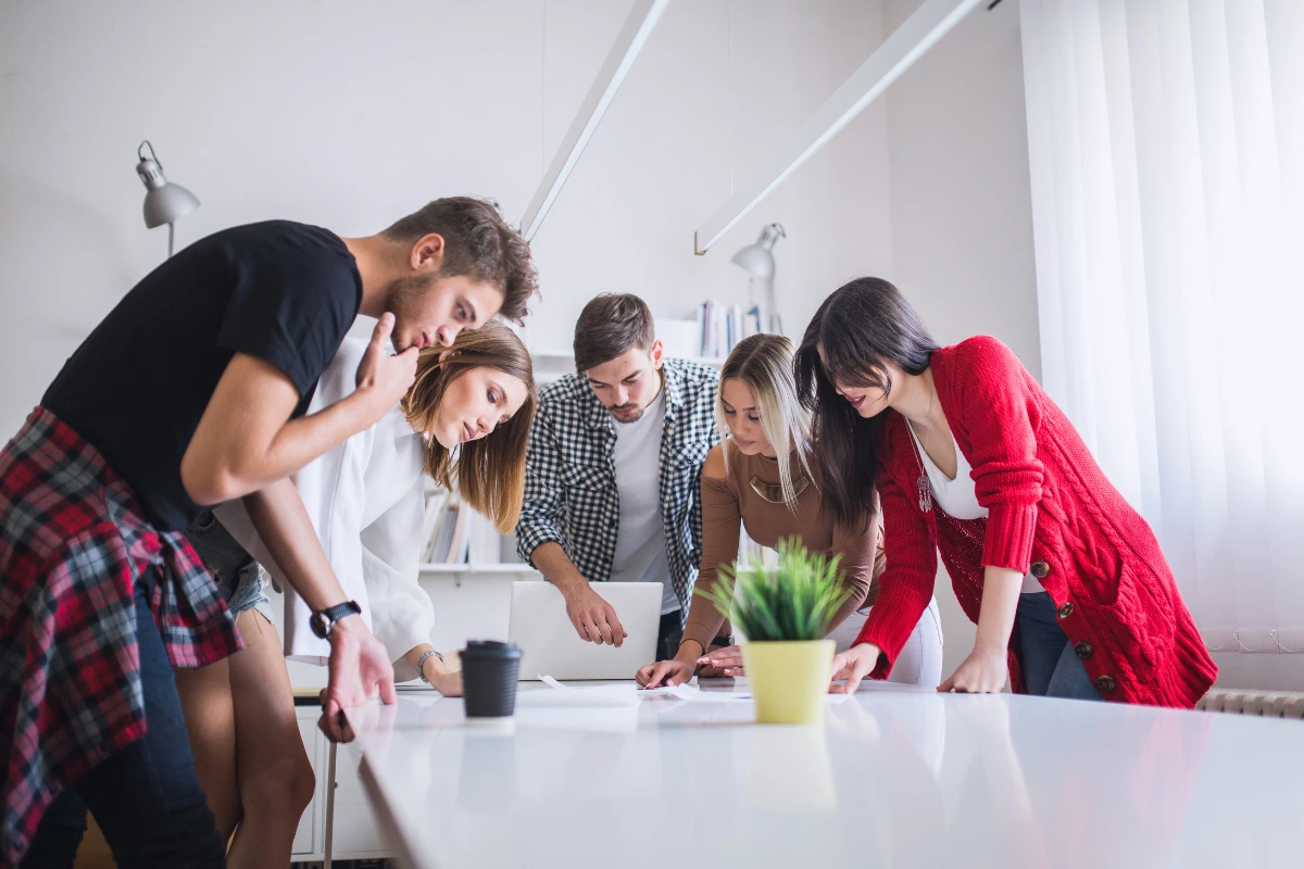 Equipe de profissionais em uma reunião criativa com quadros de post-its coloridos na parede, discutindo ideias inovadoras no ambiente de escritório moderno.