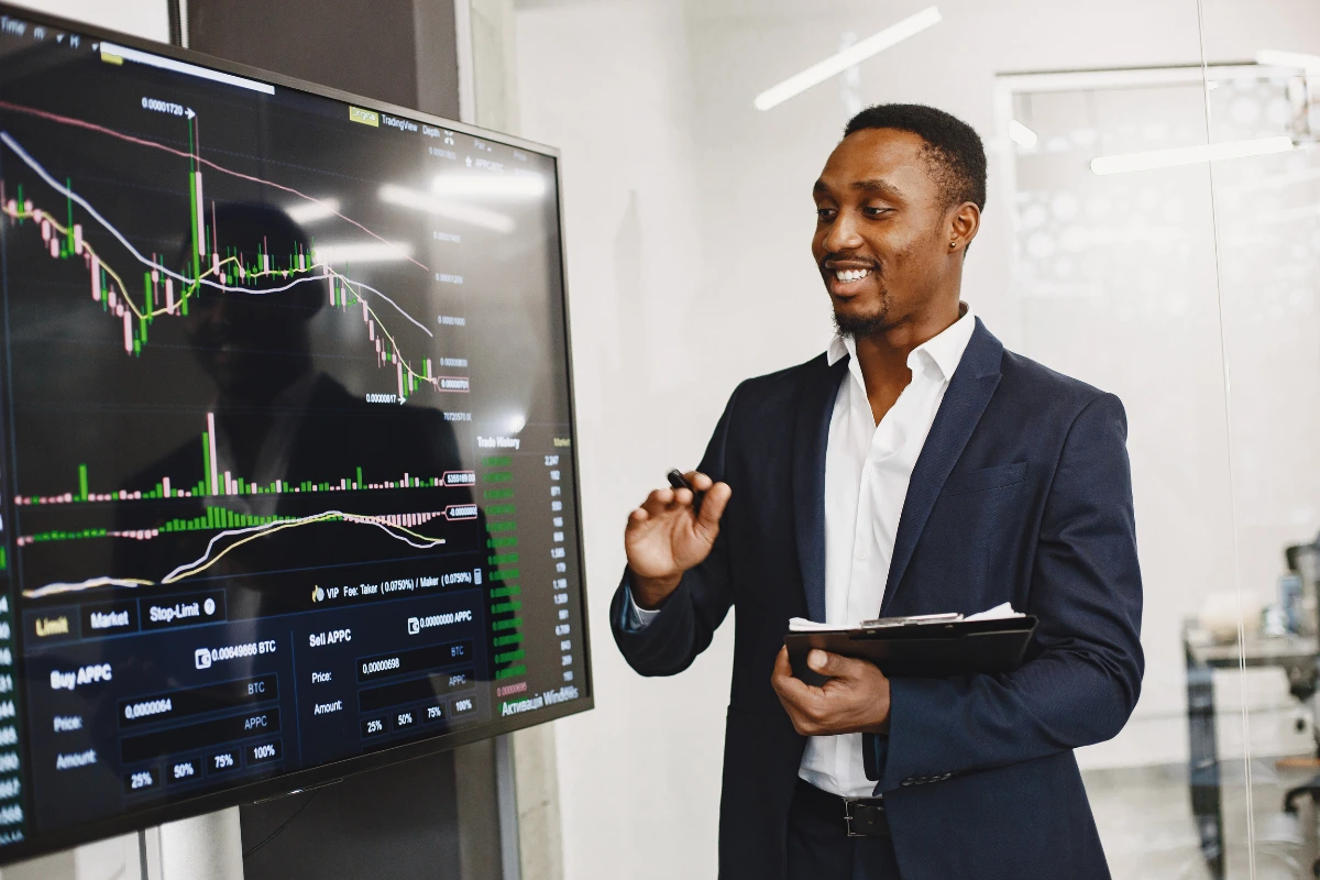 Homem de negócios analisando gráficos de investimentos em uma tela grande em um escritório moderno.