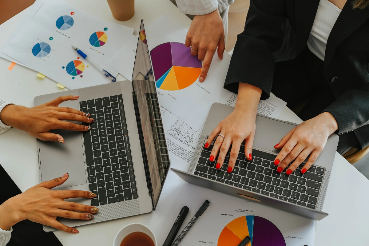 mãos de duas mulheres utilizando um computador e fazendo análises com base no estudo future of jobs report 2025