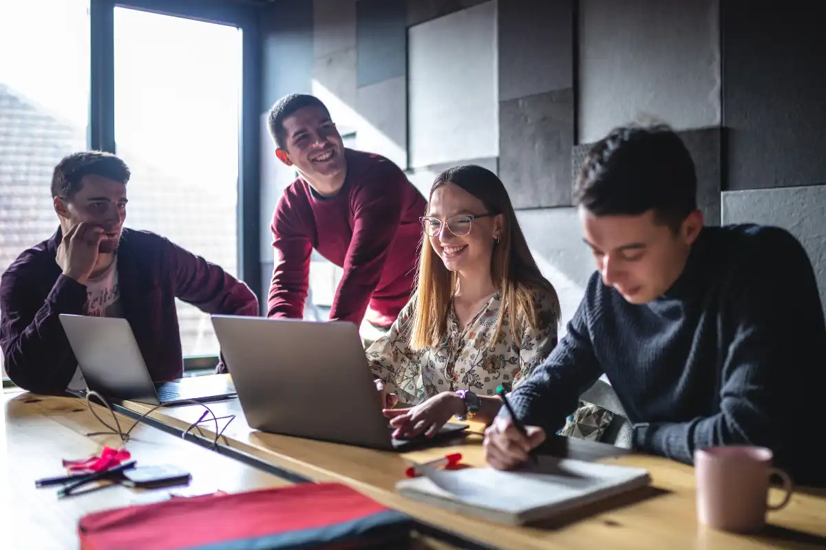 Grupo de jovens profissionais em uma reunião de trabalho em ambiente moderno, com laptops e materiais de escritório, promovendo colaboração e inovação.
